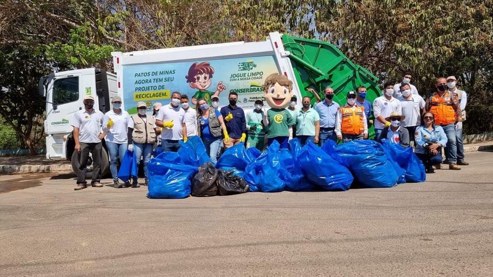 Equipe da Conserbras e voluntários com o mascote Recicladinho em frente ao caminhão de coleta em Patos de Minas